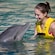 A woman smiling at a dolphin in the water at Dolphinaris in Cozumel, Mexico